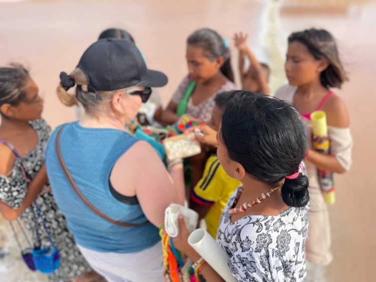 Wayúu children try to sell their handmade wallets and bracelets to Becky Hickson at the salt flats