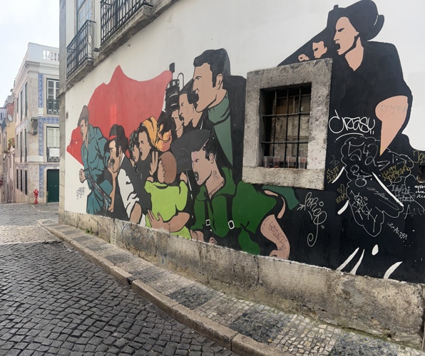 Lukisan dinding mencolok yang menggambarkan Revolusi Bunga di gang belakang lingkungan Barrio Alto di Lisbon