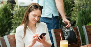 Thief Stealing Purse Of A Young Woman Using Mobile Phone. Photo by AndreyPopov, iStock