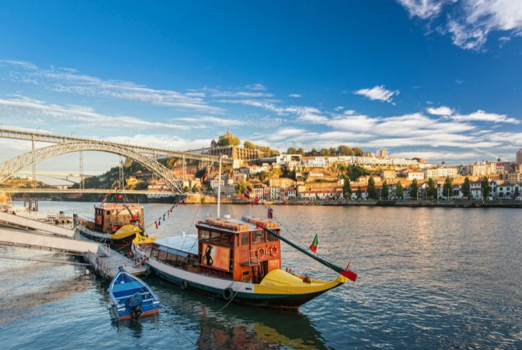 Traditional boats in the Douro River near bridge in sunny autumn day. By GavranBoris