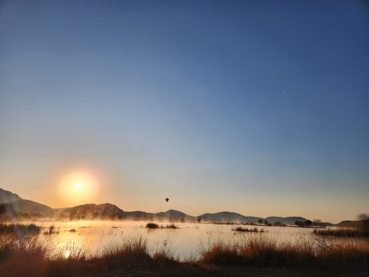 Hot air balloon rising over Pilansberg National Park at sunrise. Photo by Janine Avery