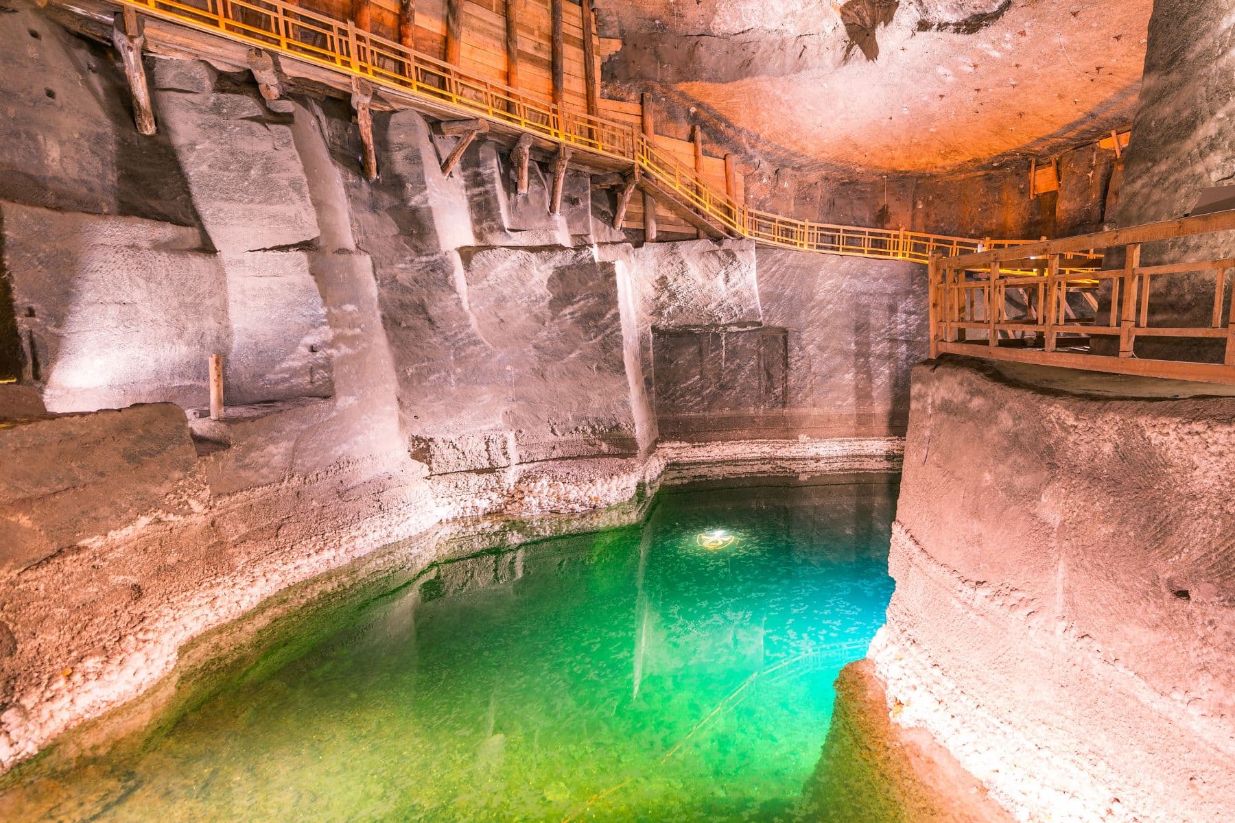 An underground brine pool in Wieliczka Salt Mine glows an otherworldly green, 442 feet below the surface. Photo by Gagliardi Photography via Canva