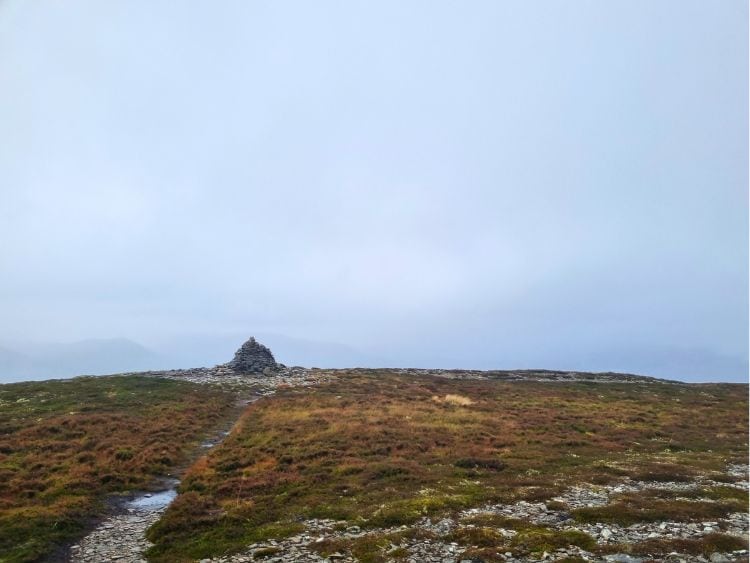 A cairn on the top of a cloudy summit. Photo by Lucy Arundell