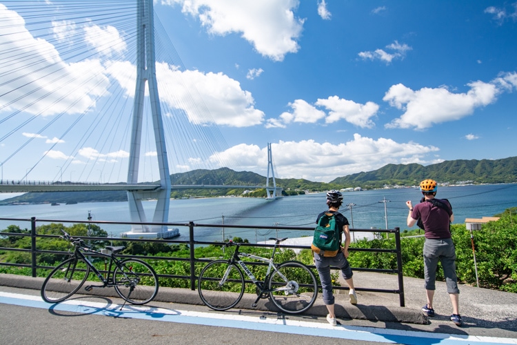 A pair of cyclists look out at one of the many bridges that connect the islands along the Shimanami Kaido