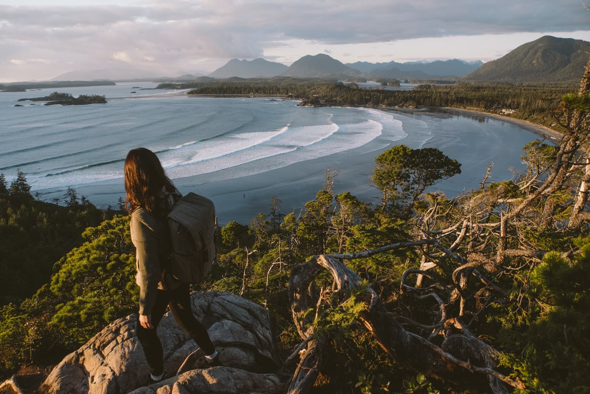 A hiker walks along the top of a trail overlooking the ocean in Tofino,