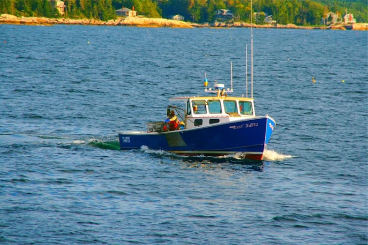 A lobsterman prepares a pot to drop over the side of his lobster boat