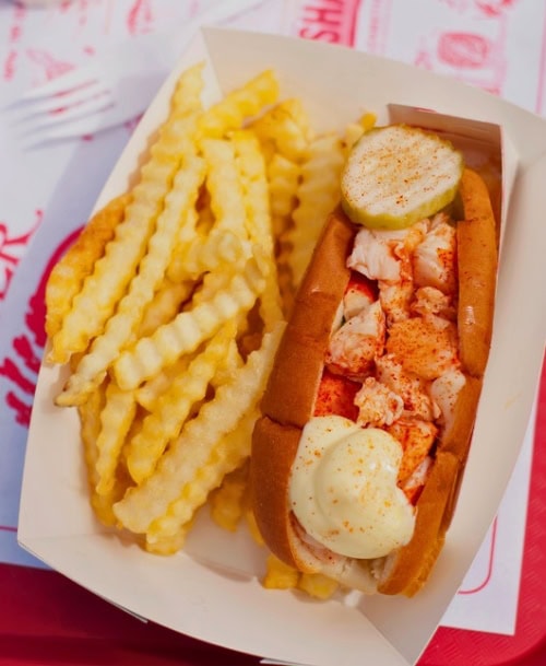 A lobster roll with fresh lobster meat in a toasted bun