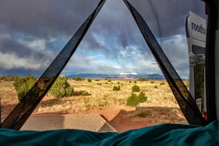 View from a Roadsurfer van of a storm rolling over the La Sal Mountains at Dead Horse Point State Park
