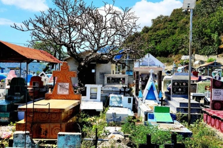 A vibrant Catholic cemetery in Timor Leste with a dense arrangement of colorful graves, mausoleums, and crypts in various shapes and materials.