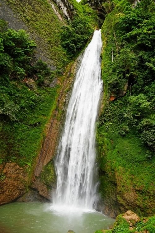 Dokomali Waterfall cascading over 100 feet with lush surroundings