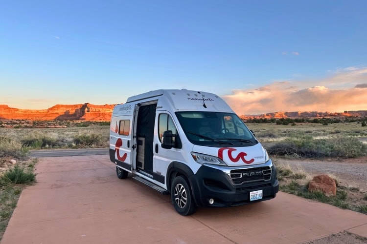 A Roadsurfer camper van parked at The Needles Campground with stunning views of Canyonlands National Park.