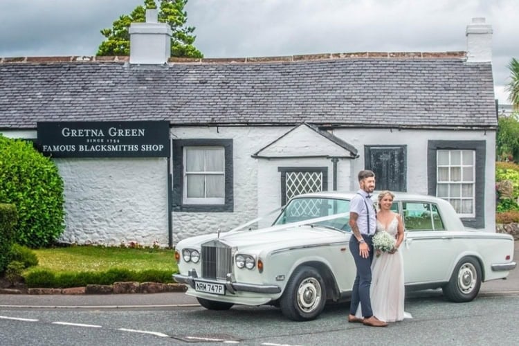 Newlyweds and car standing in front of The Famous Blacksmiths Shop, Gretna Green, Scotland