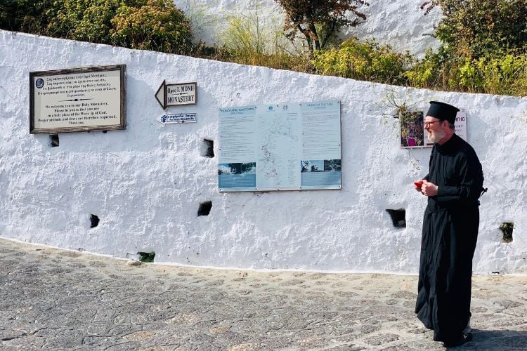 priest walking past a white wall