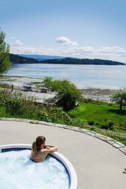 A guest relaxes in the outdoor hot tub perched above the sea