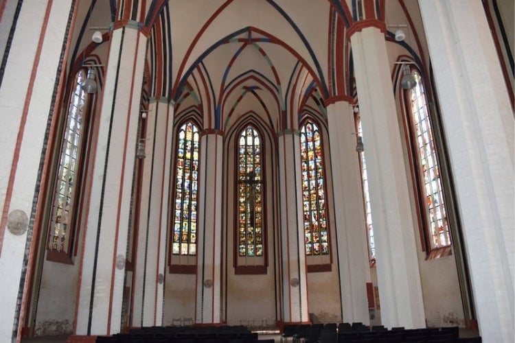 Stained glass window panels inside Marienkirche featuring Old Testament scenes, New Testament scenes, and the life of the Antichrist