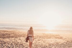 A woman in a white dress is walking on the beach