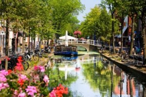 Beautiful flower adorned canal in Delft, a picturesque city in the Netherlands. Photo by Marc Moline Colom from Getty Images via Canva