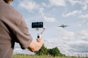 A person films an airplane with their Hohem iSteady V3 Ultra