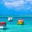 Traditional fishing boats rest in the crystalline waters off Aruba's coast. Photo by Flavio Vallenari from Getty Images Signature via Canva