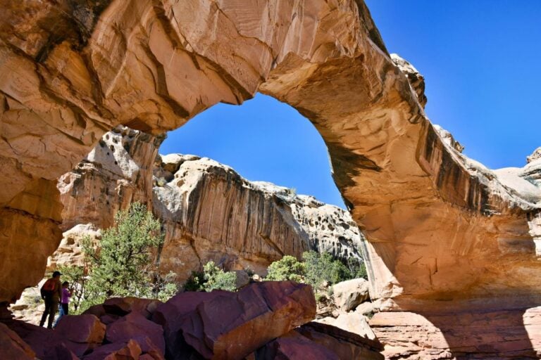 Hikers go under and around the Hinkman Bridge in Capitol Reef National Park. Photo by Tab Hauser