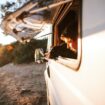 Man and dog looking out the window of a campervan. Photo by Elisabeth Jurenka, Unsplash