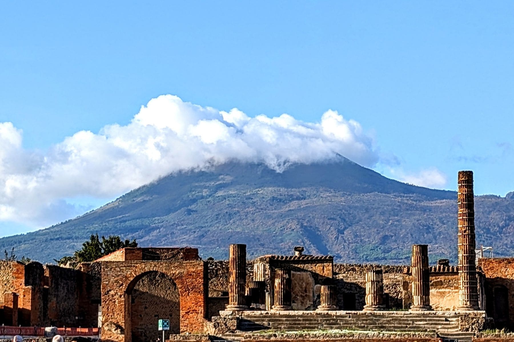 Mount Vesuvius dominates the Pompeii skyline. The Temple of Jupiter lies in the foreground. Photo by Frank Hosek