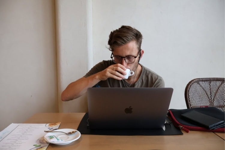 Thomas Holmes working on his laptop, drinking an espresso. Photo by Jessica Holmes