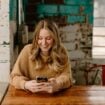 A woman sitting at a table looking at her cell phone. Photo by Brooke Cagle, Unsplash