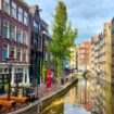 A scenic view of one of Amsterdam’s canals with gabled canal homes and a walkway with a café. Photo by Richard Varr