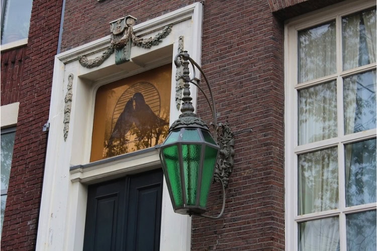 The green lantern and image of kissing love birds on the doorway of the canal house at 295 Singel, known as the former Yab Yum brothel in Amsterdam. Photo by Richard Varr