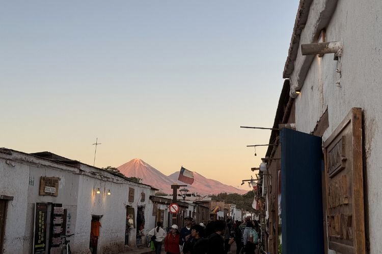 Downtown San Pedro de Atacama, Chile during sunset. Volcano Licancabur watches over the city alongside the national flag