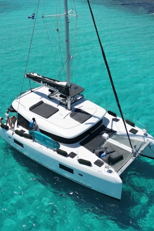 Private catamaran cruising in crystal-clear turquoise waters in the Cyclades. Photo by [Author's Name]
