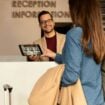 Smiling male receptionist behind the hotel counter. Photo by Getty Images, Unsplash