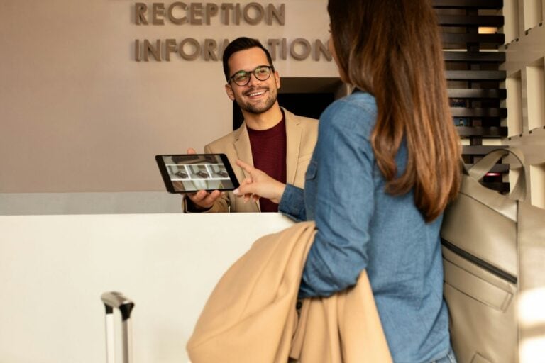 Smiling male receptionist behind the hotel counter. Photo by Getty Images, Unsplash