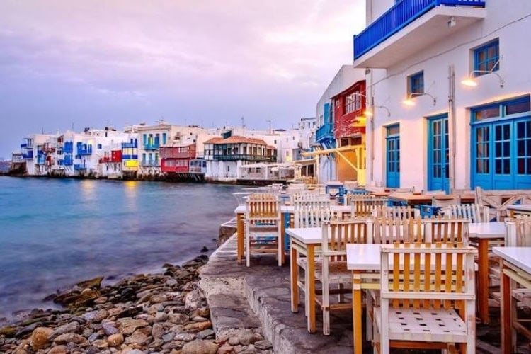 Seaside dining and colorful waterfront houses in Mykonos, Greece. Photo by [Author's Name]