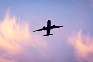 Airplane silhouette ascending against a cloudy sky. Photo by Abdelhamid Azoui, Unsplash