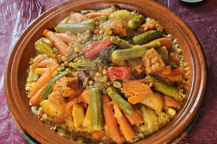 A traditional Moroccan couscous dish served with vegetables, chickpeas, and meat on a large platter.