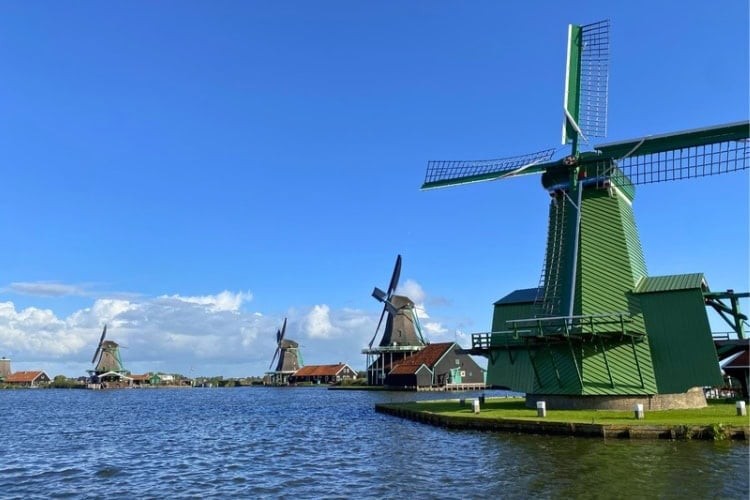 Towering windmills rising beside the river at Zaanse Schans. Photo by Huyen Tran