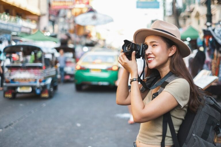 A woman taking photos on Khao San Road in Bangkok, Thailand. Photo by Getty Images, Unsplash