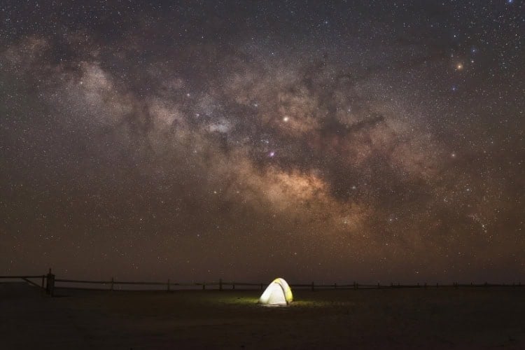 Tent camping on Assateague Island National Seashore under the stars. Photo by Michael Ver Sprill from Getty Images via Canva