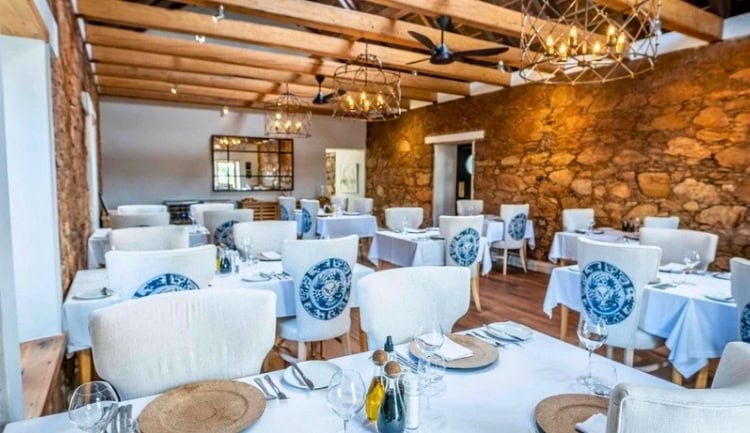 Dining room with original stone walls and exposed beams. Photo by Diane McLeish
