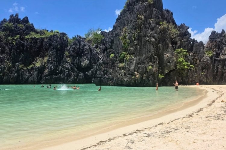 Travelers swim beside limestone cliffs at an island beach in El Nido, Palawan, Philippines. Photo by Kurl Ivan I Fernandez