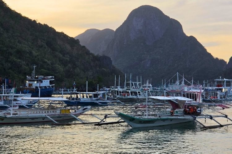 Outrigger boats rest in El Nido harbor as sunset settles behind limestone cliffs in Palawan, Philippines. Photo by Kurl Ivan I. Fernandez