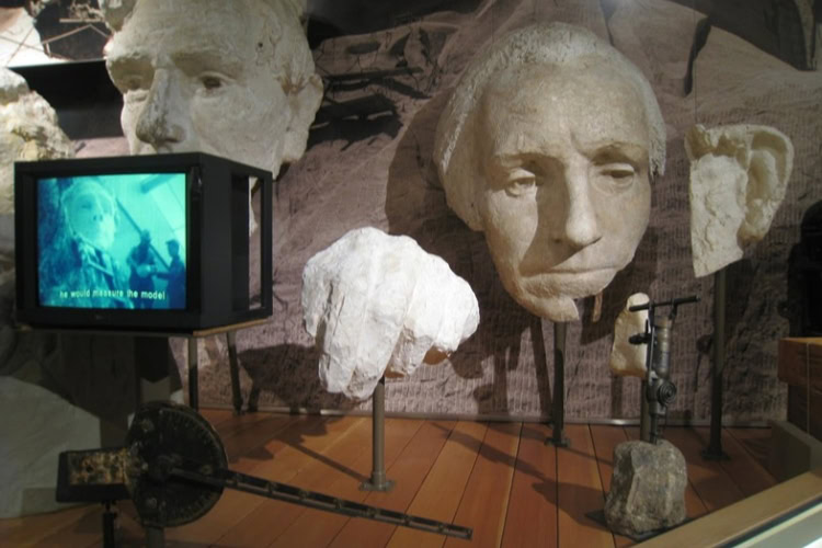 Plaster models of Abraham Lincoln and George Washington on display in the Exhibit Hall inside the Lincoln Borglum Visitor Center. These models could be suspended on the mountain for the carvers to reference while working. Photo by Frank Hosek