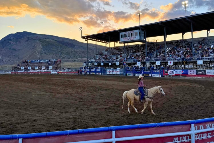 A rider crosses the arena at Cody Nite Rodeo as evening sets in. Photo by Isabella Miller