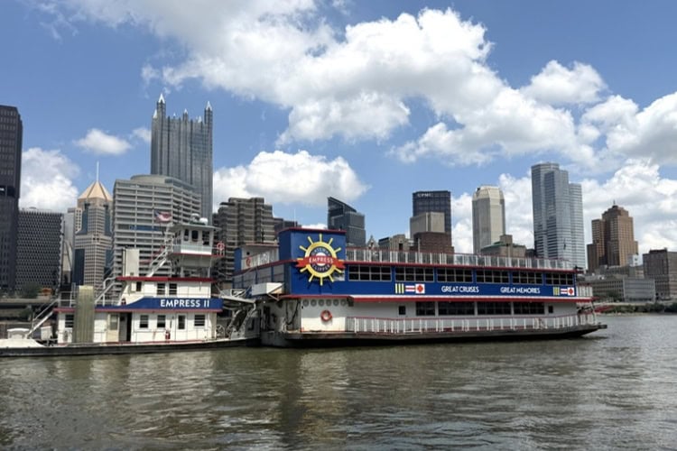 Boat on Pittsburgh's rivers with a backdrop of tall buildings. Photo by Debbie Stone