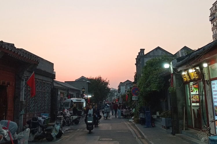 Evening falls over a traditional hutong neighborhood in Beijing, where locals and visitors share the narrow streets. Photo by Shivika Singh