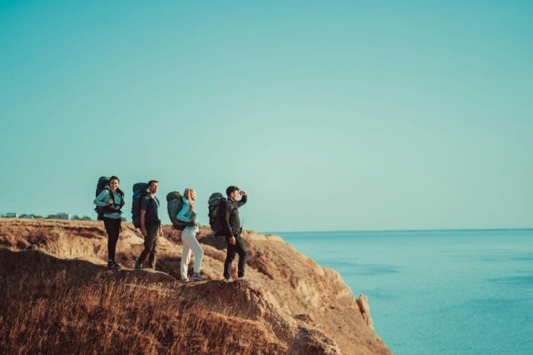 Four travelers on a mountain top above the sea. Photo by Getty Images, Unsplash