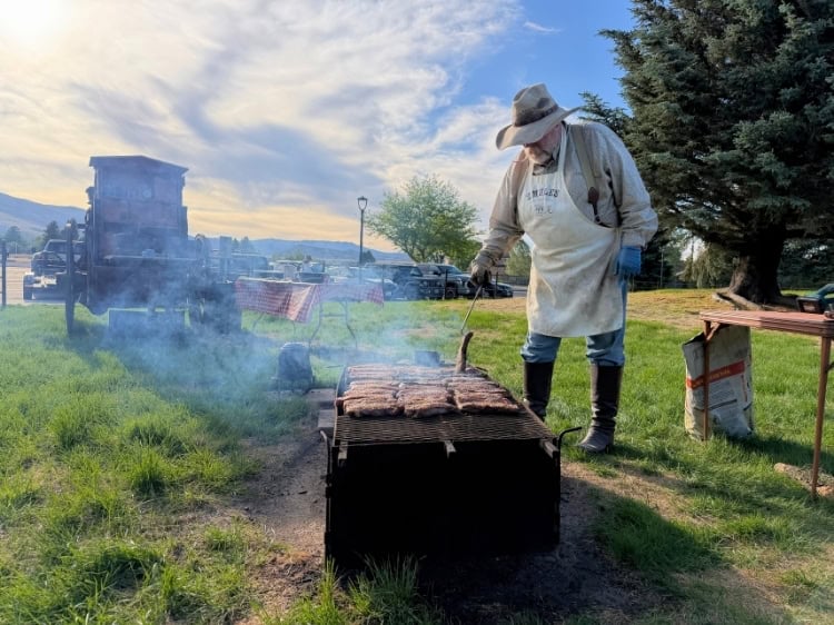 Rich Herman tends the fire at 2 Mules Chuckwagon, where he and his wife Deb grill steaks to order for every guest. Photo by Isabella Miller