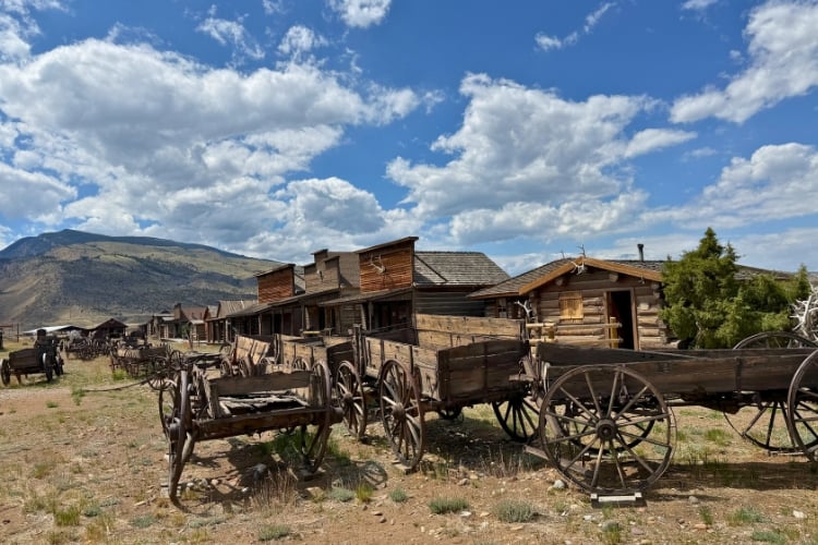 Weathered wagons line the dirt paths of Old Trail Town, a collection of 28 historic buildings relocated from across Wyoming and Montana. Photo by Isabella Miller